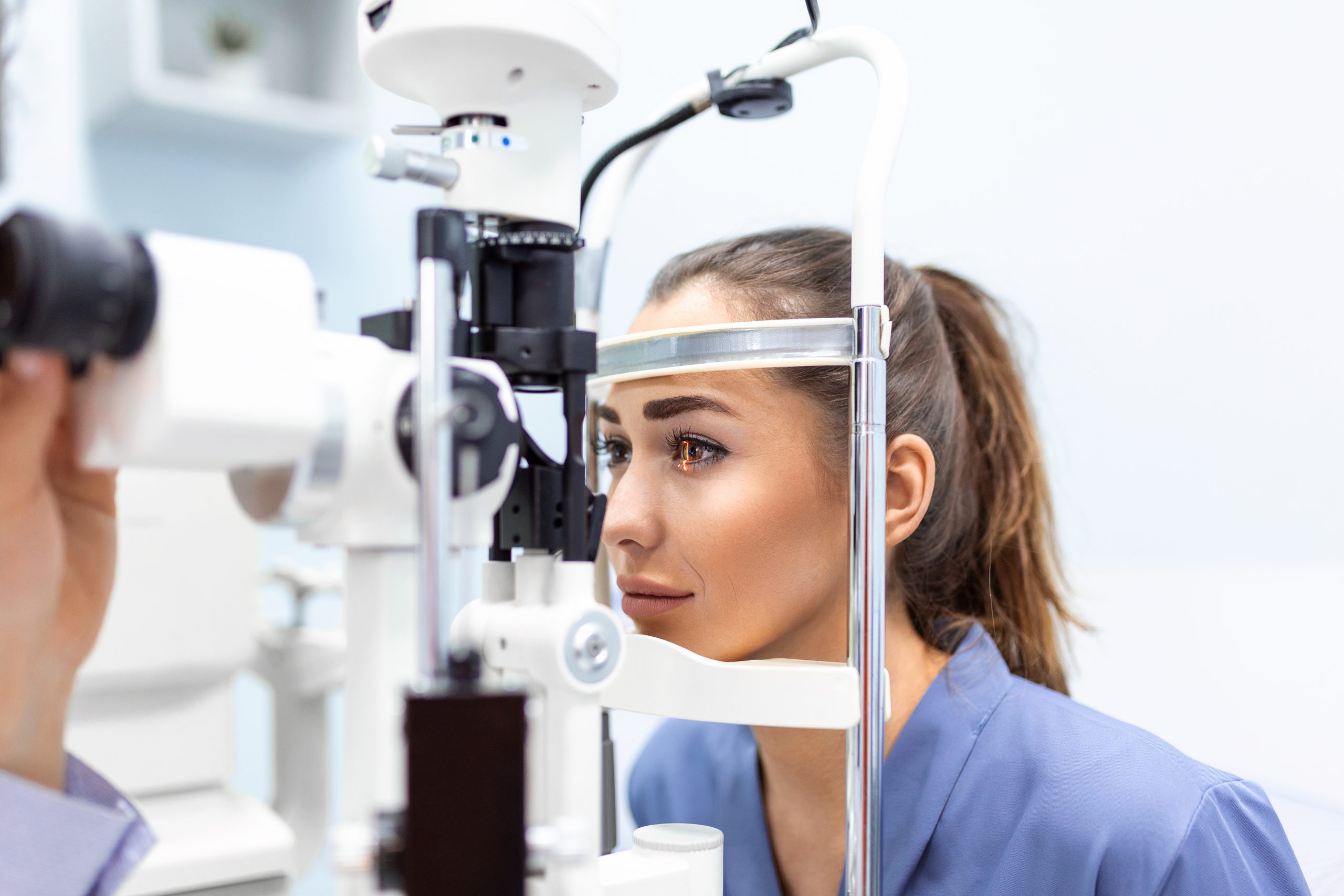attentive optometrist examining female patient slit lamp ophthalmology clinic young beautiful woman is diagnosed with eye pressure special ophthalmological equipment scaled